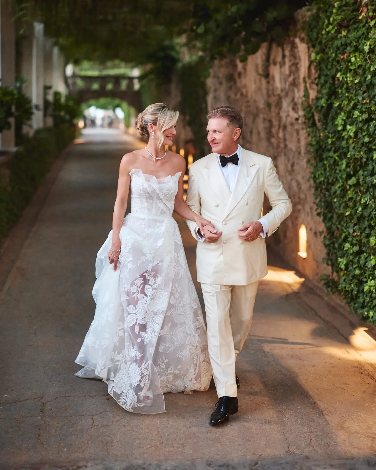 couple walks the wisteria tunnel at villa cimbrone